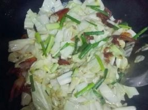 油锅加热，将生姜碎和腊肉倒入锅中翻炒，炒到5~6成熟时放入卷心菜翻炒，撒上葱段
