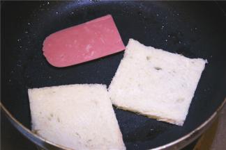 利用锅中剩余的油，火腿和面包片入锅慢煎至微焦