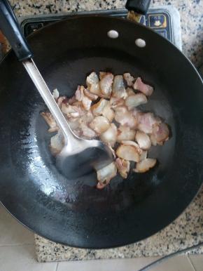 锅中倒入适量的油，烧热后转中火放入腊肉爆香，再放上蒜片和干辣椒炒香