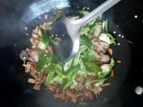 调大火，放上笋干和青椒快速翻炒，炒出香味后加入料酒、生抽、盐和鸡精，翻炒均匀出锅