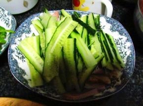 把切好的猪肉铺放在盘底，上面放上黄瓜片