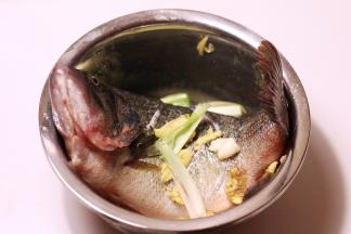 鱼洗干净，去除内脏和血水，鱼身斜切几刀，撒上2茶匙盐和1汤勺料酒，生姜、大蒜拍碎，葱白切段，均匀涂抹在鱼身，盖上保鲜膜放进冰箱腌30分钟左右