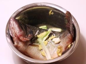 鱼洗干净，去除内脏和血水，鱼身斜切几刀，撒上2茶匙盐和1汤勺料酒，生姜、大蒜拍碎，葱白切段，均匀涂抹在鱼身，盖上保鲜膜放进冰箱腌30分钟左右