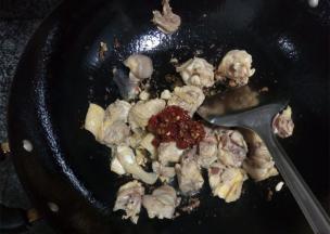 把沥干的鸡肉放入锅中煸炒，倒入豆瓣酱增味