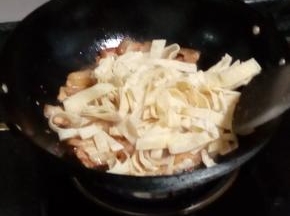 五花肉煸干后，把面皮倒进锅中混炒