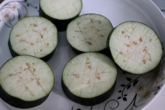 茄子去蒂清洗干净，把茄子切成厚薄匀均的茄子段，切好的茄子段切面切花刀，方便烹饪入味