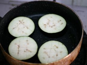 平底锅内倒少许的油，油温4分热的时候放入茄子。小火煎至表面呈金黄色，捞出控油