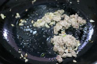 锅内底油烧热，倒入葱姜蒜末，炒出香味。放入肉末，炒至变色