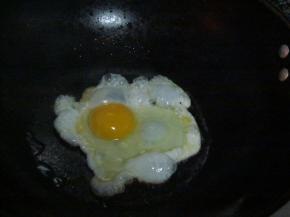 锅中放油，油热后调小火，打一颗鸡蛋入锅，煎成荷包蛋装盘备用