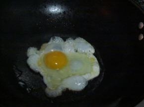 锅中放油，油热后调小火，打一颗鸡蛋入锅，煎成荷包蛋装盘备用