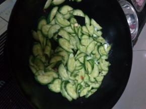 炒锅中剩余的油加热，翻入蒜片炒香，把黄瓜片放入翻炒