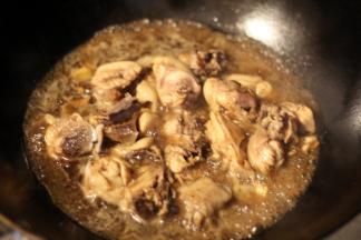 鸡肉翻炒变色后倒入米酒、酱油、白糖炒均，加盖大火烧开，转中小火慢炖