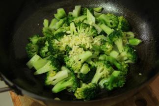 炒锅加热后倒入食用油，置入焯水后的西兰花，依次加盐，味精翻炒至入味后加入蒜泥