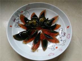 将剥好的松花蛋切成蒜瓣状，拿一个盘子，摆成花瓣状待用