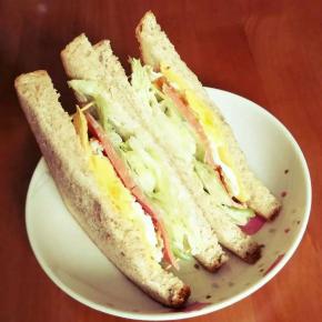 将涂抹好沙拉和少许浓稠酸奶的吐司片叠放至芝士片。三明治基本完成，可用牙签四角固定，然后将其呈三角切开，入盘。