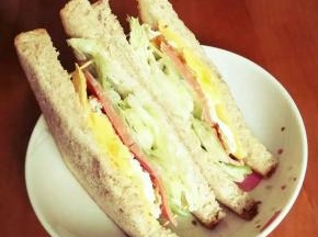 将涂抹好沙拉和少许浓稠酸奶的吐司片叠放至芝士片。三明治基本完成，可用牙签四角固定，然后将其呈三角切开，入盘。