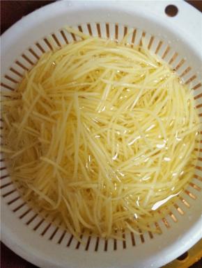 将土豆削皮切丝，切好后即刻用水冲洗，洗去土豆表面淀粉。冲洗3遍后，放入清水中浸泡，以防土豆氧化变黑。