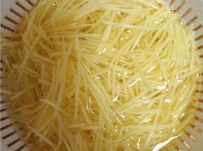 将土豆削皮切丝，切好后即刻用水冲洗，洗去土豆表面淀粉。冲洗3遍后，放入清水中浸泡，以防土豆氧化变黑。