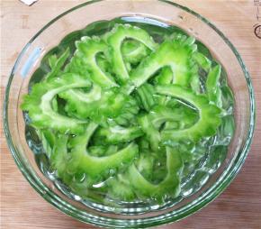 处理好的苦瓜斜切成片，放入水中浸泡，以保持翠绿的色泽。