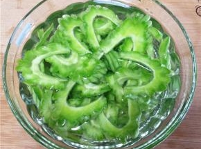 处理好的苦瓜斜切成片，放入水中浸泡，以保持翠绿的色泽。