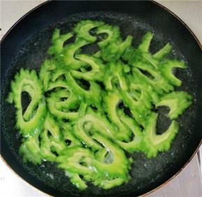 锅内放水，大火烧开，放入苦瓜，煮至水再次沸腾时过30秒左右立刻捞出过凉水，才能保证苦瓜的爽脆的口感。沥水后的苦瓜放入调料调味。辣椒面、鸡精、花椒、黑芝麻适量。锅内烧热油浇至苦瓜上，炝出调料的香味。