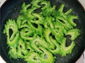 锅内放水，大火烧开，放入苦瓜，煮至水再次沸腾时过30秒左右立刻捞出过凉水，才能保证苦瓜的爽脆的口感。沥水后的苦瓜放入调料调味。辣椒面、鸡精、花椒、黑芝麻适量。锅内烧热油浇至苦瓜上，炝出调料的香味。
