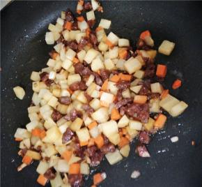 热锅冷油，放入洋葱蒜末爆香后加入腊肠煸炒出油，最后放入土豆和胡萝卜丁继续翻炒，并加入少许生抽、耗油提味，花椒粉和鸡精、盐少许继续翻炒。
