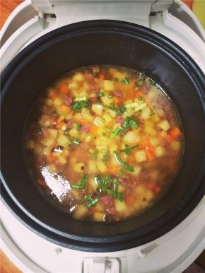 炒制4分熟后放入洗净的大米在电饭煲中，并加适量水和葱花，水的分量和普通蒸米饭的一样，按下煮饭键。