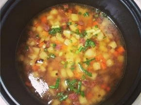 炒制4分熟后放入洗净的大米在电饭煲中，并加适量水和葱花，水的分量和普通蒸米饭的一样，按下煮饭键。