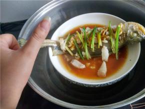 适量的盐、蒜蓉、姜丝、五花肉、葱丝放在鱼上。特别留意要在鱼肚子放姜丝。
