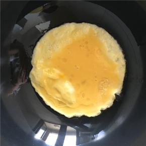 倒入打散的鸡蛋，不要急着翻炒待鸡蛋，先做成两面金黄的鸡蛋饼（刚开始先不急着炒碎鸡蛋而是做成鸡蛋饼，是因为蛋液由于空气被加热在鸡蛋饼内部形成气泡的作用，使鸡蛋内部结构比较疏松，可以达到外部金黄内部滑嫩的效果，吃起来也略有蓬松感）