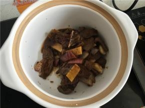 关火起锅，将爆炒后的牛肉和调味料一起倒入准备好的砂锅。
