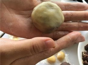 手上拍点面粉防粘，取皮在手心压扁，馅放皮上，慢慢推动饼皮，转动收口。