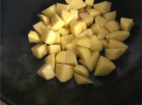 大蒜切片，炒锅入油后倒入大蒜片爆香，再加入土豆。