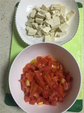 将西红柿剥皮，切碎（越碎越好），豆腐切拇指大小的丁。