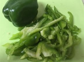 大青椒横向剖开，去除里面的芯后，切成丝。注意青椒的根蒂有大量农药残留，最好拿掉。