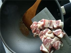 热锅凉油，放入冰糖，小火加热至冰糖完全融化并开始变黄时，下牛腩。