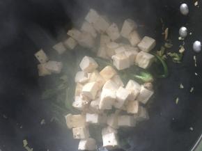 待菠菜炒至7成熟，倒入豆腐，将豆腐翻至菠菜下面水煮