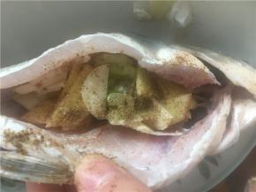 将姜片、葱、蒜片塞进鱼肚子里，撒上盐、花椒
