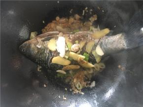 开中火，将腌制好的鱼放入锅中，煎至两面金黄，并将腌制鱼的佐料一同倒入锅中