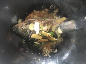 开中火，将腌制好的鱼放入锅中，煎至两面金黄，并将腌制鱼的佐料一同倒入锅中