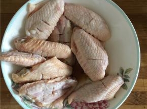 在处理好的鸡翅中倒入料酒和酱油腌制5分钟