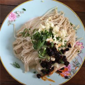 在捞出的金针菇中放入葱花、蒜末和辣酱，并撒上少许盐