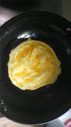 在锅中倒入少量的油，倒入打散的鸡蛋，移动锅，煎成蛋饼。