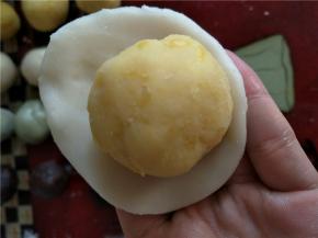 将冰皮压成饼状，放入奶黄馅收口。