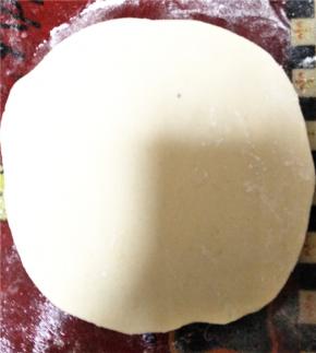 发酵好的面团加入少许小苏打揉至均匀且面团表面光滑，随后将面团分为若干小面团待用，取其中一份小面团用擀面杖擀至如下样子。