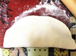 如下所示，将另一半未放馅料的面皮翻上去，用手压紧面皮边缘。