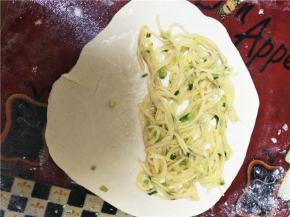 发酵好的面团加入少许小苏打揉至均匀且面团表面光滑，随后将面团分为若干小面团待用，取其中一份小面团用擀面杖擀至如下样子，并在其一半处放馅。