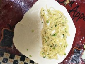 发酵好的面团加入少许小苏打揉至均匀且面团表面光滑，随后将面团分为若干小面团待用，取其中一份小面团用擀面杖擀至如下样子，并在其一半处放馅。