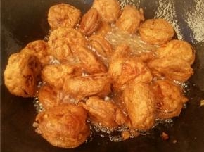 在将炸好装盘的茄饼倒入锅中再炸一遍